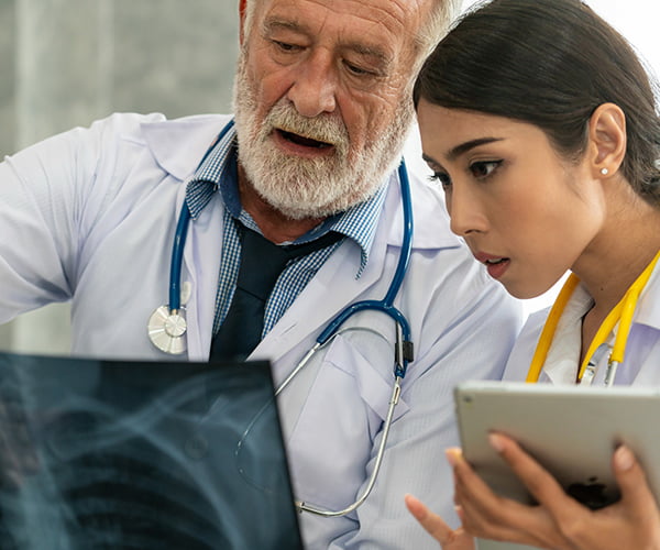 Senior team member showing an xray to a younger medical professional/doctor