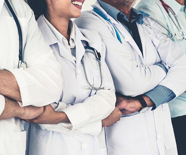 Medical team smiling shoulder to shoulder with arms crossed