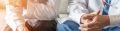 picture of a doctor with folded hands consulting a patient holding their arm